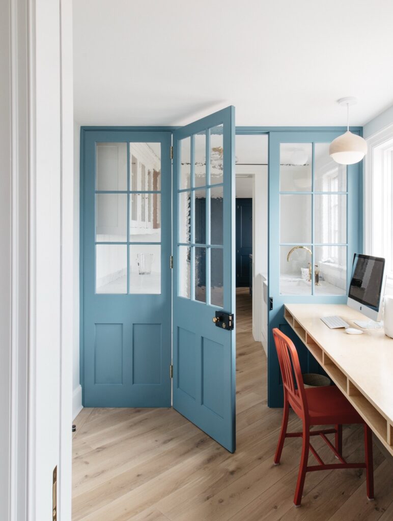Light blue door in house with window pane, brown side table with macbook