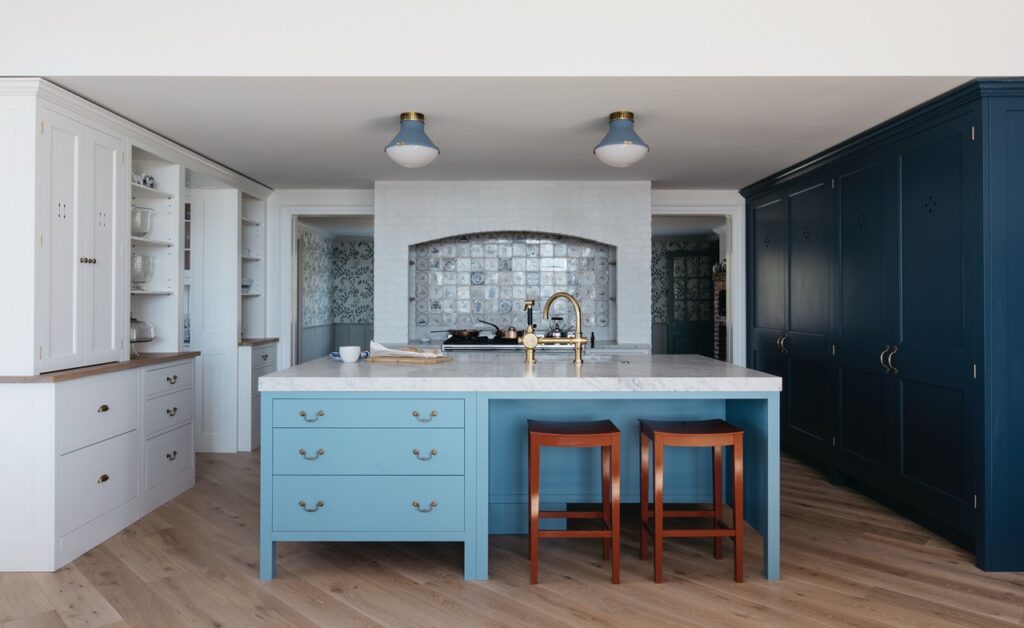 Bespoke kitchen with light blue painted island with wall cupboards painted in a dark blue