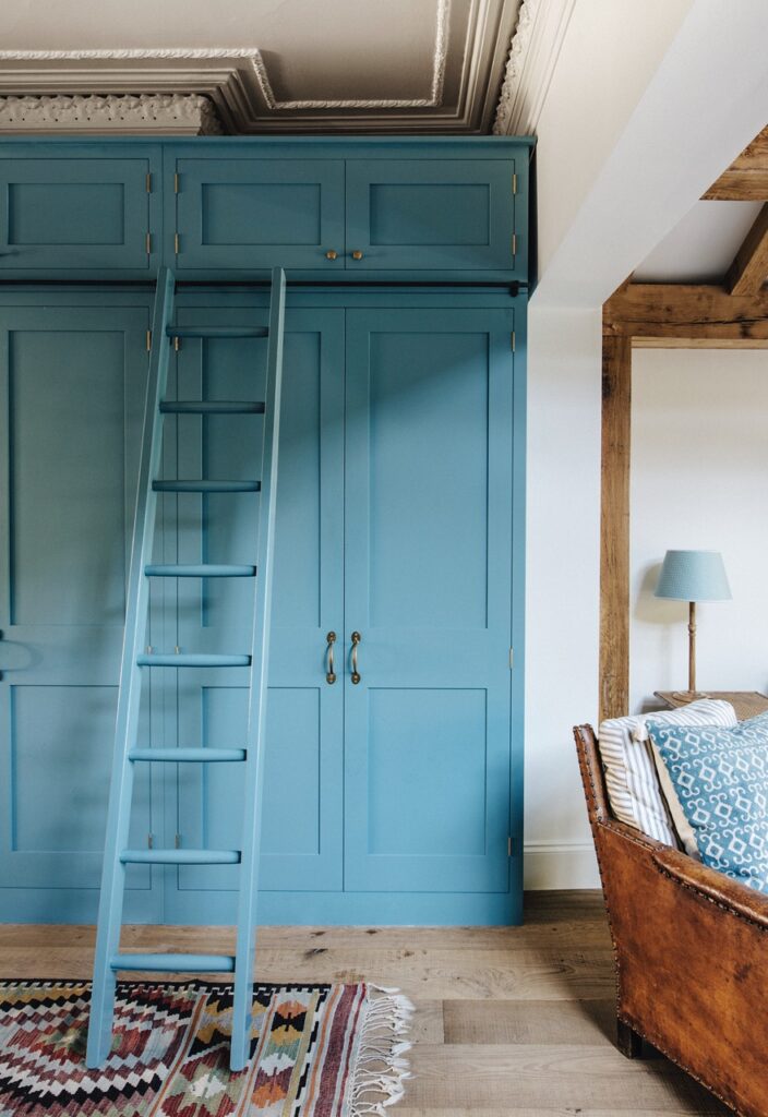 Bespoke light blue cupboard with ladder next to leather living room chair