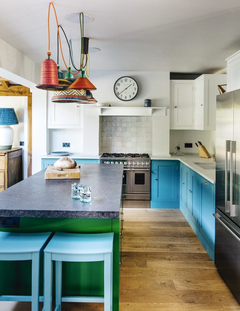 A bespoke kitchen featuring tall, clean-lined white top cabinetry with brass pull hardware and light blue bottom cabinets