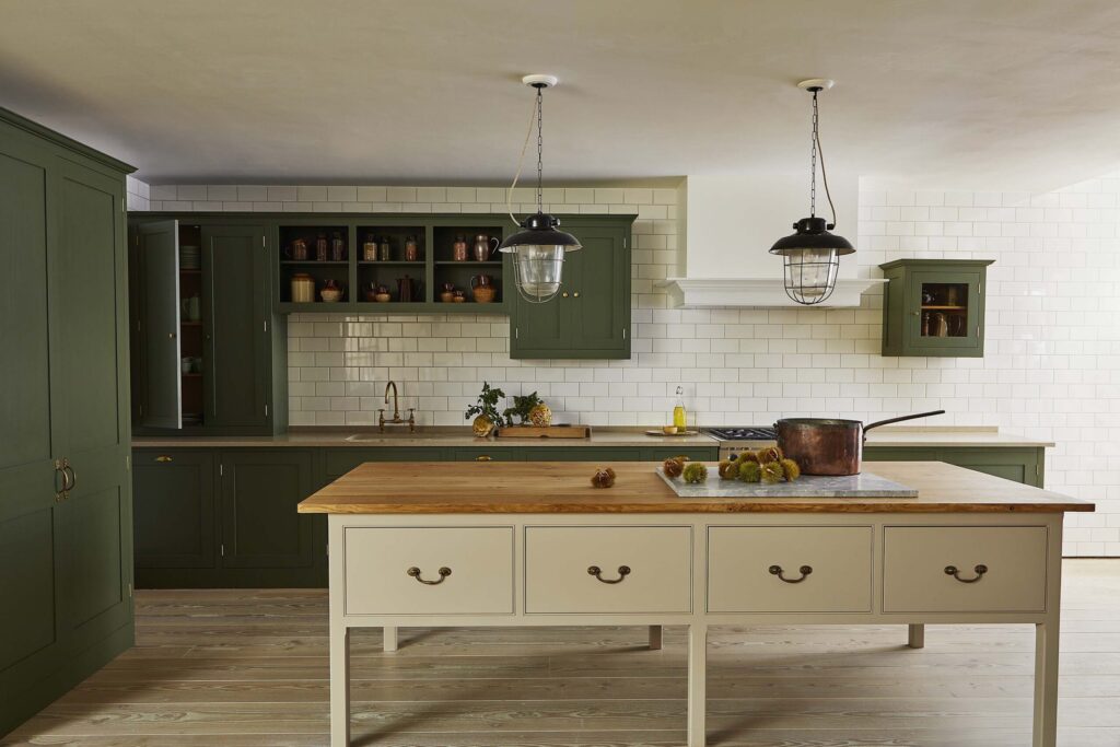 Kitchen featuring custom cabinetry painted in a deep green, set against dark wood floors and illuminated by warm under-cabinet lighting