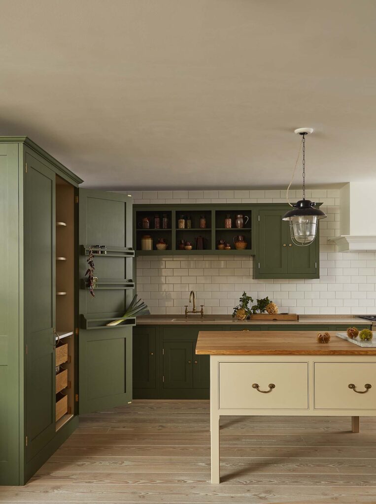Kitchen featuring green custom cabinetry, set against dark wood floors and a beige wooden work table