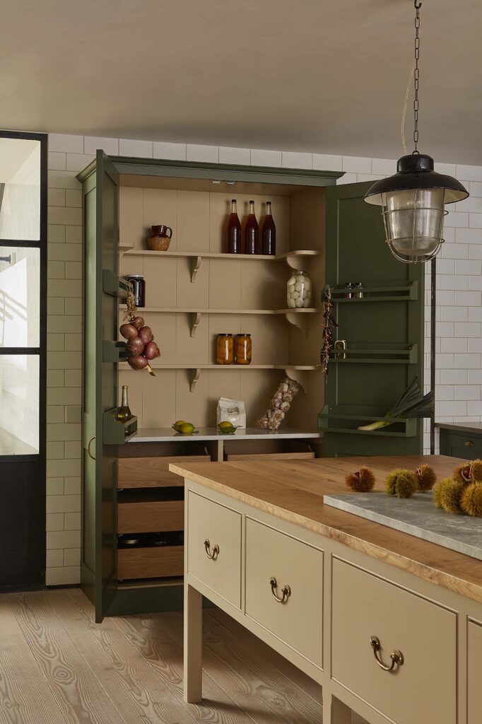 Floor, Wall, and tall cupboards filled with pantry items, painted in an olive green with wooden working table