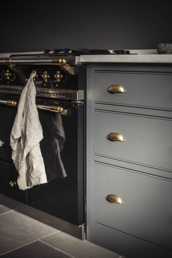 Bespoke kitchen featuring a striking deep blue-black island paired with light neutral tall larder cupboards and a cooker run