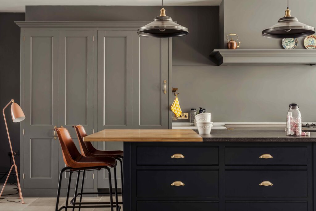 Room with pale blue-gray fitted cabinetry, polished wood and stone counterop, and an elegant brass hardware