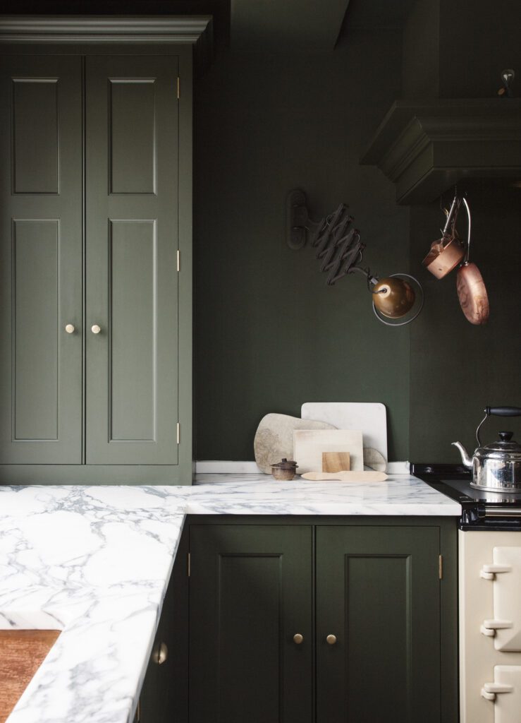 Top and floor kitchen cupboards painted in an army green with white marble countertops