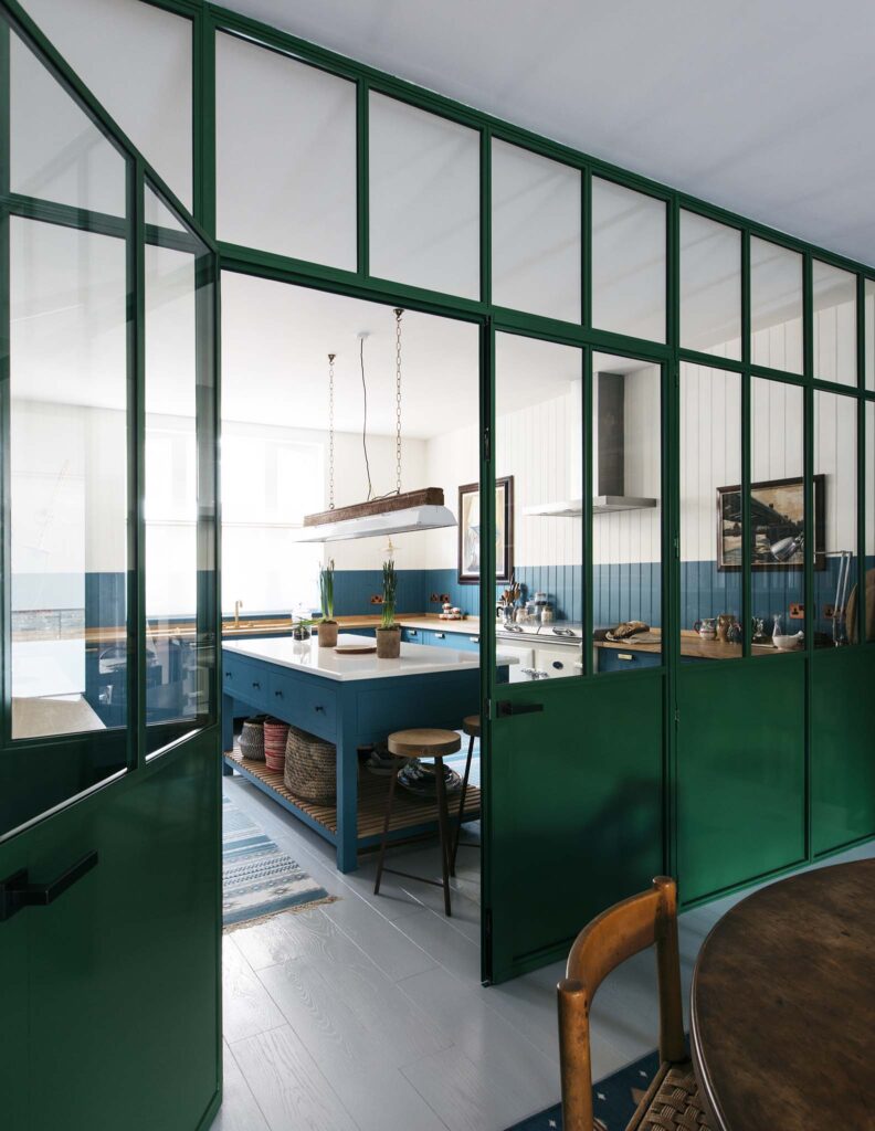 Green divider doors with clear windows separating spare room with blue cabinet kitchen