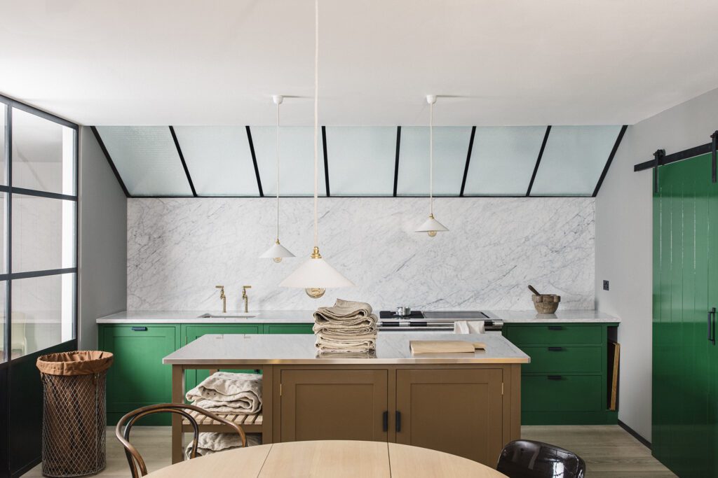 Bespoke kitchen with pickle green cupboards and cabinets, marble counters, and island with folded napkins