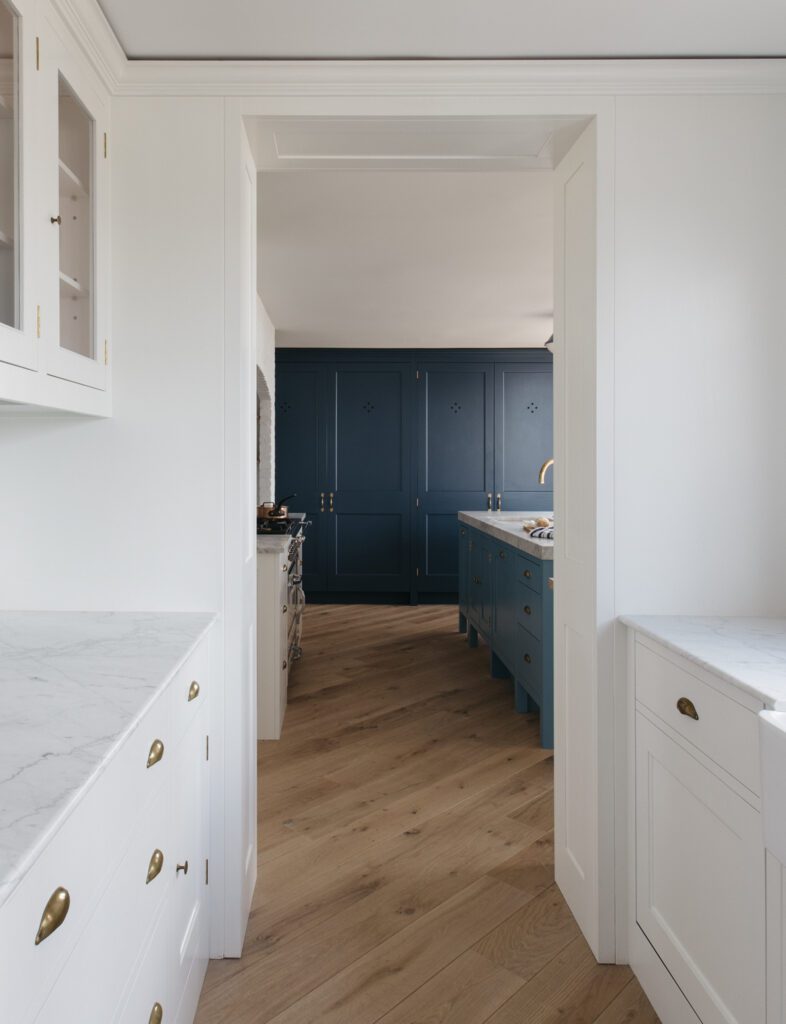 Bespoke kitchen with dark blue cupboard, white cabinets, and white countertops