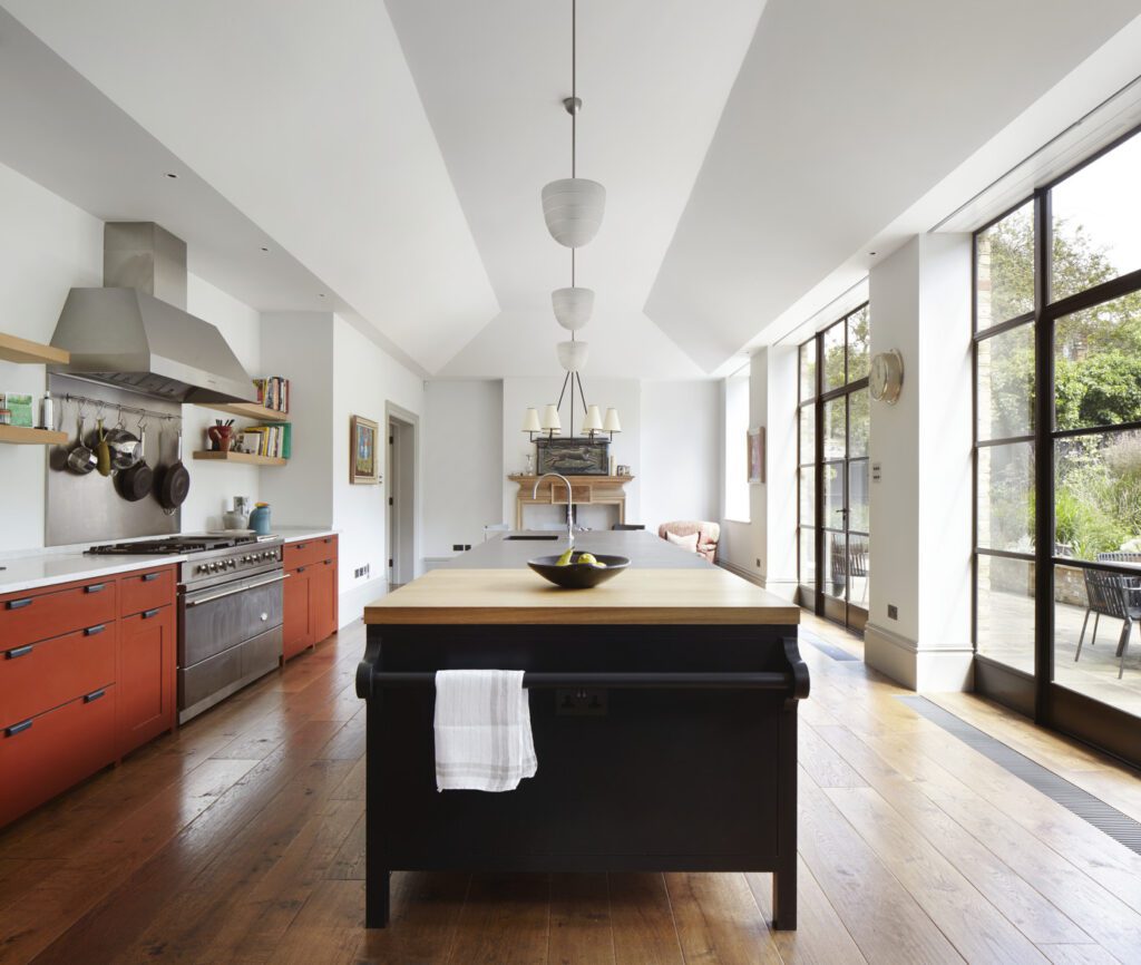 Bespoke kitchen with island painted in dark gray, rusty nail red floor cupboards, and open windows