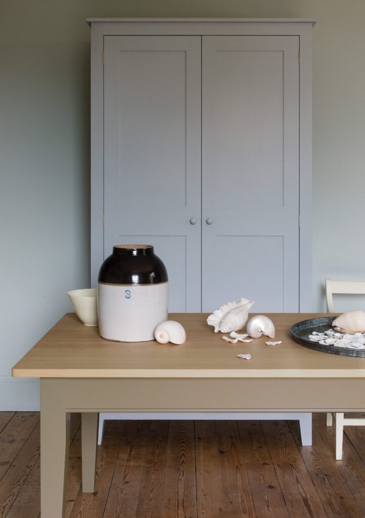 Seashells on top of a light wood table in front of white dresser