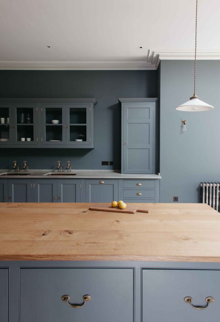 Country kitchen featuring cabinetry and walls painted in a unified neutral color, centered around a contrasting Oak table