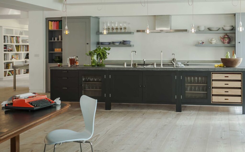 New York loft kitchen featuring sleek black cabinetry, table with typewriter, and exposed shelves