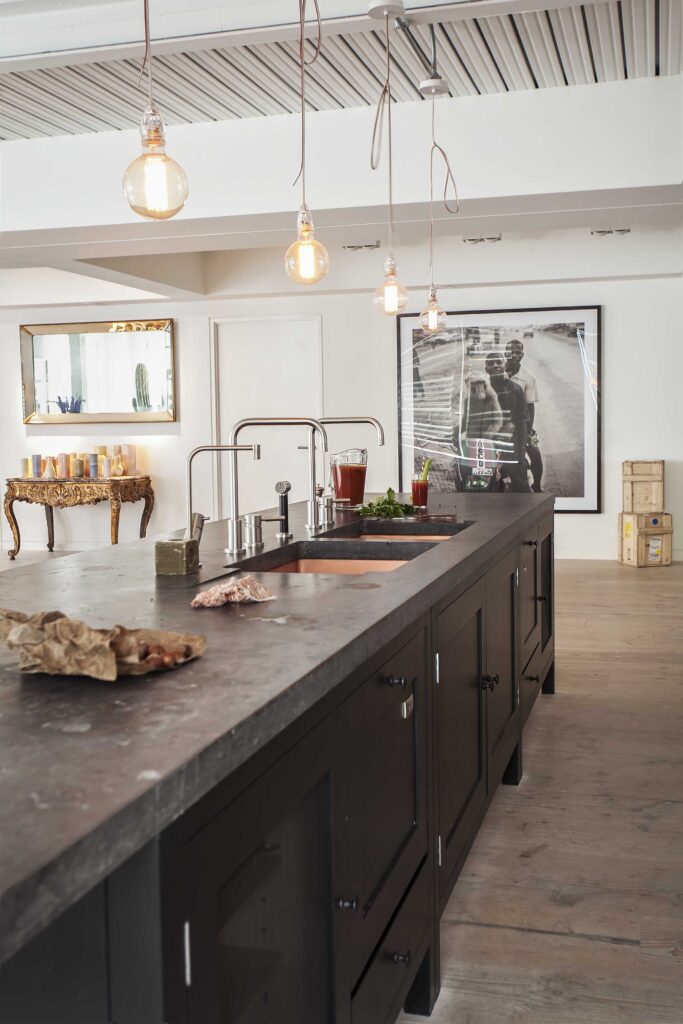 Large kitchen island painted in coal scuttle black with dual faucets and niche wall art