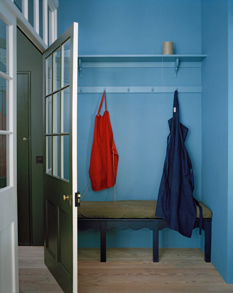 Light blue painted wall and peg in mudroom with the bench seat painted in dark blue