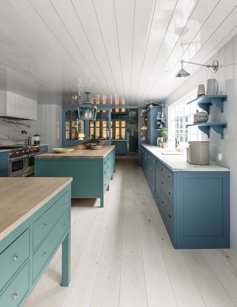a bespoke English kitchen featuring two distinct islands. the cabinetry is painted with a high-gloss, creamy green