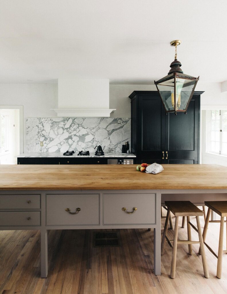 Bespoke worktable painted in Woollen Flump brown, black tall cupboards, and white marble backsplash