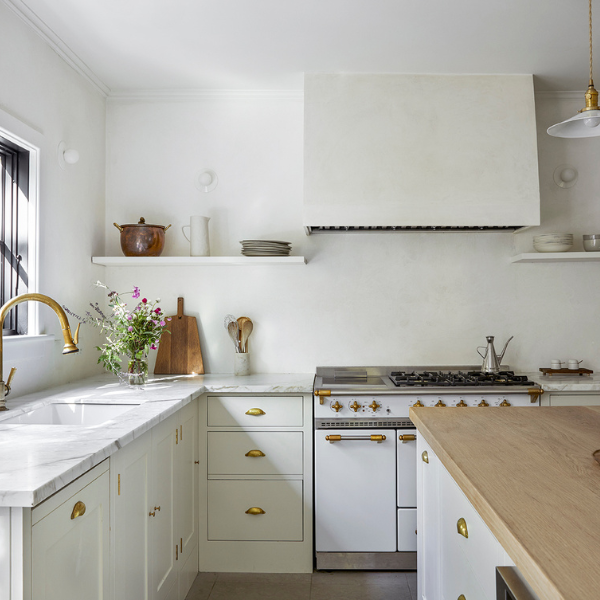 Bright white kitchen with brass hardware, open shelving, and a farmhouse-style range.