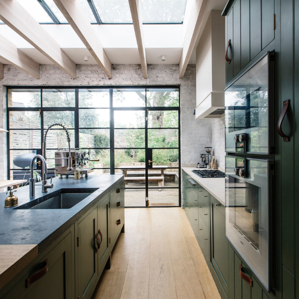 Modern kitchen with skylights, dark cabinetry, long island, and large grid windows.