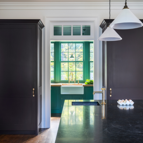 Bold kitchen with dark cabinetry, white walls, and a green-accented sink area framed by a window.